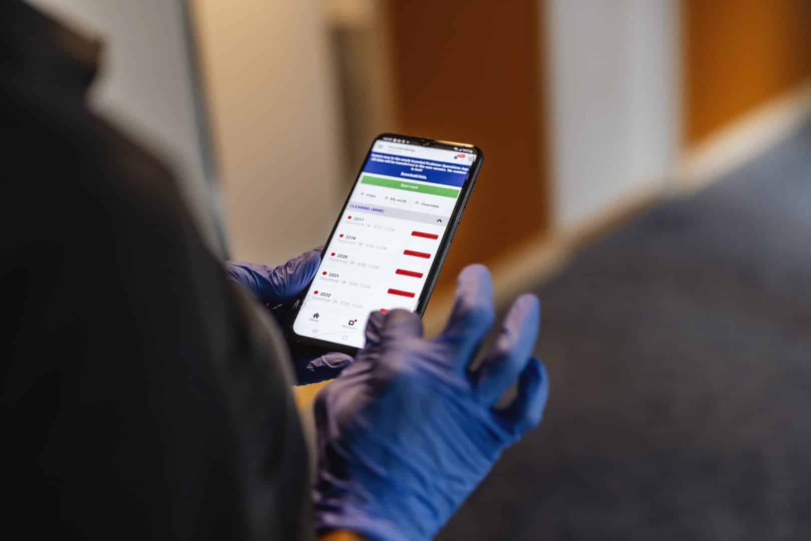 Ability-medarbeider sjekker romstatus i housekeeping-appen på mobil