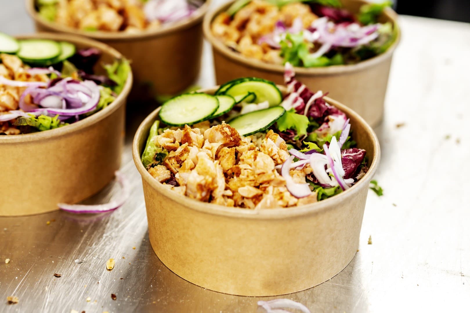 Stacked lunch bowls with fresh salad, ready for delivery