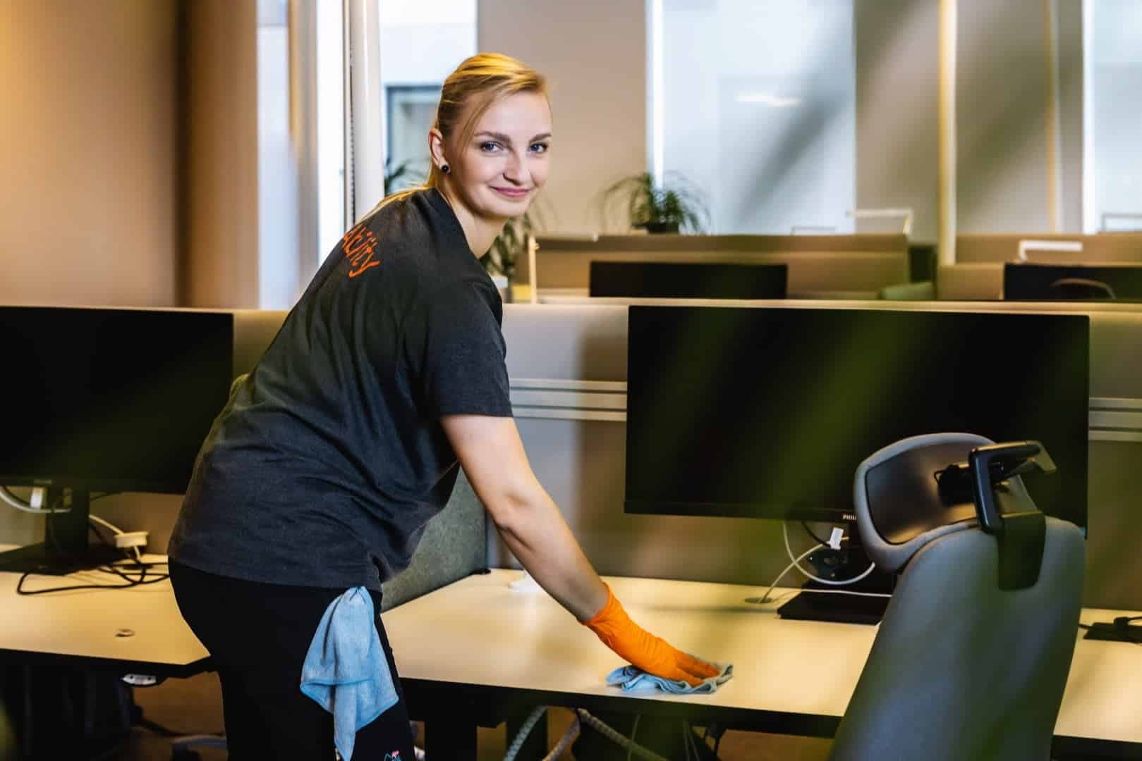 Renholder fra Ability tørker over en kontorpult med mikrofiberklut