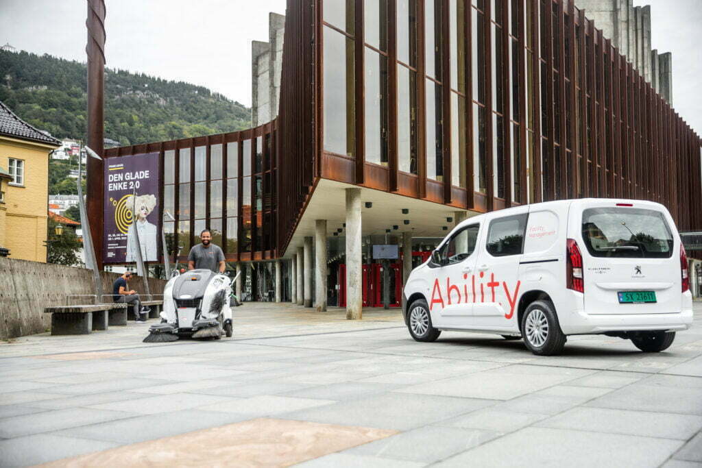 En Ability-varebil og en medarbeider med en stor vaskemaskin utenfor Grieghallen i Bergen
