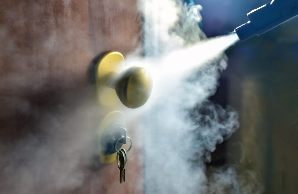 Beskrivende bilde fra Shutterstock: Dørhåndtak blir desinfisert av fog