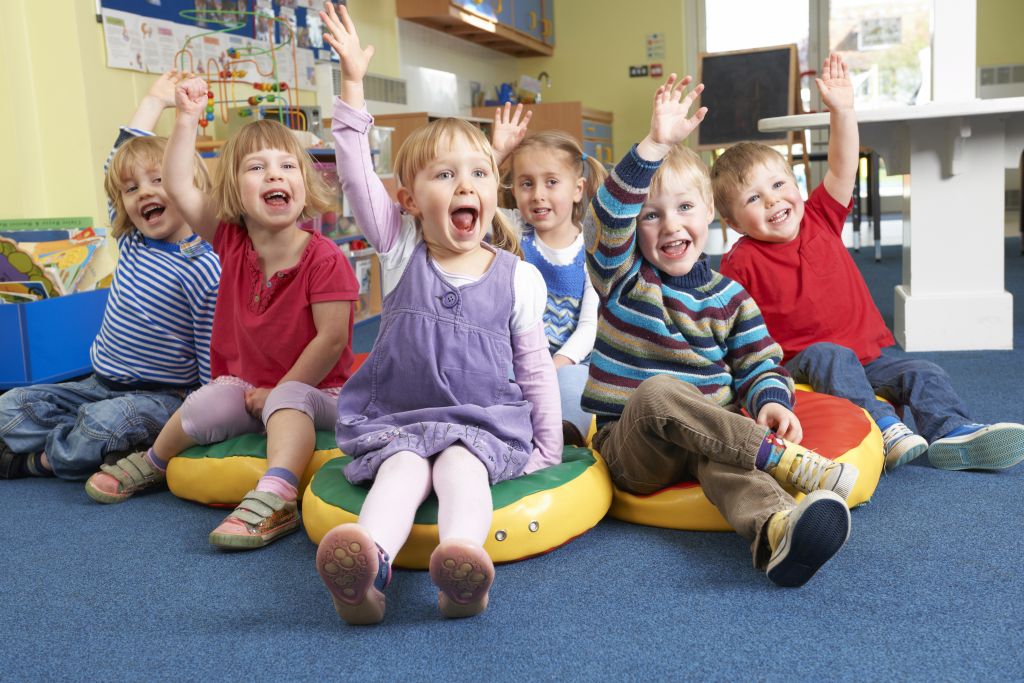 Barn rekker opp hånden i en barnehage