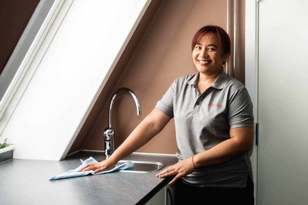 En renholder vasker benken på et kjøkken